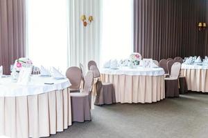 set da tavola fantasia per cena con composizione floreale nel ristorante, sfondo interno di lusso. matrimonio elegante decorazione per banchetti e articoli per il cibo organizzati dal servizio di catering su tavola bianca. foto