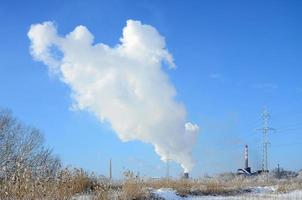 il industriale pianta è collocato dietro a il paludoso terreno, coperto con neve. grande campo di giallo giunchi foto