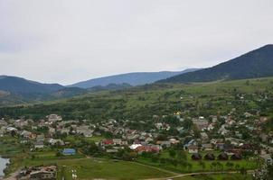 un' bellissimo Visualizza di il villaggio di mezhgorye, carpazi regione. un' lotto di Residenziale edifici circondato di alto foresta montagne e lungo fiume foto