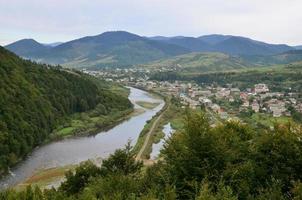 un' bellissimo Visualizza di il villaggio di mezhgorye, carpazi regione. un' lotto di Residenziale edifici circondato di alto foresta montagne e lungo fiume foto