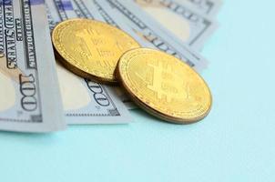 d'oro bitcoin e centinaio dollaro fatture bugie su leggero blu sfondo foto