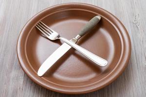 Marrone piatto con attraversamento coltello, cucchiaio su grigio foto