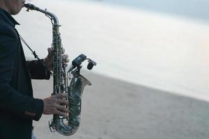 musicista uomo giocando sassofono su il spiaggia. foto