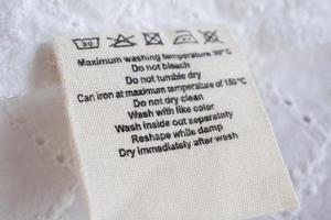 lavanderia cura lavaggio Istruzioni Abiti etichetta su tessuto struttura sfondo foto