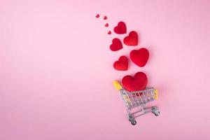 rosso cuore forma con shopping carrello su rosa sfondo per amore nozze e san valentino giorno foto