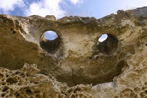 superiore di il scogliera nel il modulo di un' sorridente viso con occhi e un' bocca. struttura, Esposto alle intemperie calcare sfondo. il parte inferiore di il antico mare. astratto sfondo. foto