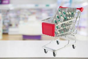 capsule di pillole medicinali nel carrello sul bancone della farmacia con sfocatura sullo sfondo sfocato degli scaffali della farmacia foto