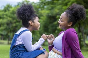 africano americano madre è dando Pinky promettere per sua giovane figlia mentre avendo un' estate picnic nel il pubblico parco per amore e felicità concetto foto