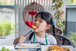 asiatico giovane ragazza mangiare pollo pepite veloce cibo su tavolo. foto