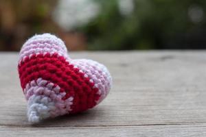 uncinetto multicolore cuore forma fatto a partire dal filato su di legno tavolo nel il giardino per San Valentino giorno. foto