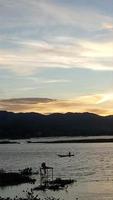 silhouette di un' uomo pesca nel il pomeriggio. tramonto su lago limbo, Indonesia foto