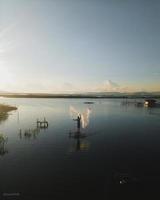 silhouette di un' uomo pesca nel il pomeriggio. tramonto su lago limbo, Indonesia foto