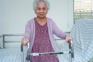 camminata del paziente di disabilità della donna anziana asiatica con il deambulatore nell'ospedale di cura, concetto medico. foto