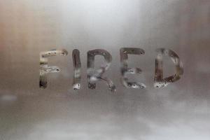il parola licenziato manoscritto su bagnato finestra bicchiere a nuvoloso tempo metereologico foto