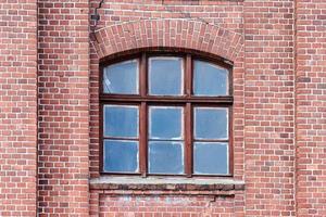 una finestra di vetro ad arco sul vecchio muro di mattoni rossi foto