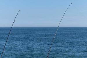 due canne da pesca sullo sfondo blu dell'oceano o del mare, spazio di copia. aspettando il bottino più grande. sport di rilassamento meditativo. foto