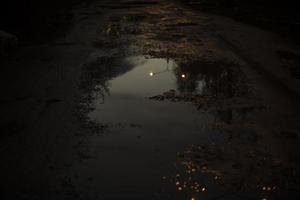 grande pozzanghera nel scuro. riflessione di leggero nel pozzanghera. cattivo strada nel Russia. foto