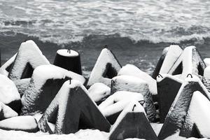 frangiflutti in cemento ricoperti di neve, fondale marino invernale foto