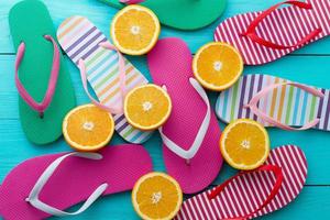 estate divertimento volta, Flip flop. pantofole e arancia frutta su blu di legno sfondo. finto su. superiore Visualizza. sandali foto