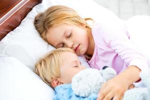 bambina e ragazzo che dorme sul letto bianco foto