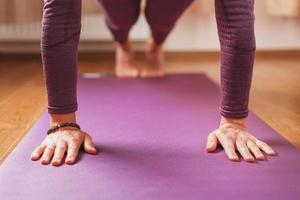 un' ragazza fa yoga asana su un' lilla tappeto nel il vivente camera foto