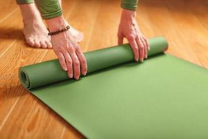 un' donna raccoglie un' verde stuoia dopo un' yoga classe foto