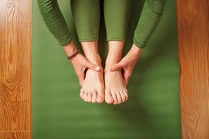 un' donna fa yoga su un' verde tappeto a casa nel il vivente camera. foto