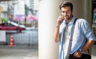 il attività commerciale uomo parlando con inteligente Telefono su loro modo. sensazione contento e rilassante, casuale giovane uomo d'affari indossare completo da uomo giacca e spalla Borsa. foto