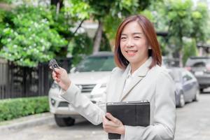 bellissimo giovane donna Tenere auto chiavi e passaggio per asiatico femmina cliente. foto