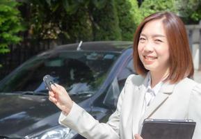 bellissimo giovane donna Tenere auto chiavi e passaggio per asiatico femmina cliente. foto