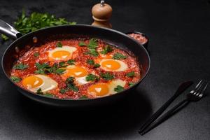 Shakshuka, un' piatto con fritte uova con pomodoro salsa, dolce Pepe, aglio, cipolle, spezie e erbe aromatiche foto