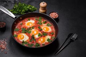 Shakshuka, un' piatto con fritte uova con pomodoro salsa, dolce Pepe, aglio, cipolle, spezie e erbe aromatiche foto