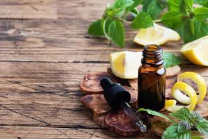 Limone agrume frutta essenziale olio e menta, aromaterapia olio naturale biologico cosmetico su rustico legna sfondo. foto