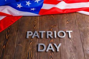 il parole patriota giorno di cui con argento metallo lettere su di legno tavola superficie con spiegazzato Stati Uniti d'America bandiera foto