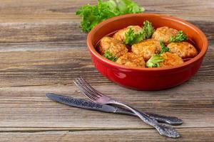 Polpette nel pomodoro salsa nel un' ciotola su di legno tavolo. foto