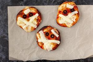 mini Pizza come mummia per bambini con formaggio, olive e ketchup. divertente pazzo Halloween cibo per bambini. foto