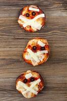 mini Pizza come mummia per bambini con formaggio, olive e ketchup. divertente pazzo Halloween cibo per bambini foto