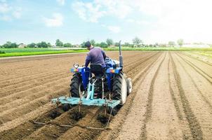 contadino su un' trattore fabbricazione righe su un' azienda agricola campo. preparazione il terra per piantare futuro Ritaglia impianti. coltivazione di suolo per piantare. agroindustria, agroalimentare. agricoltura, europeo terreno agricolo. foto