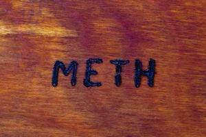 il parola meth per metanfetamine - bruciato di mano con bruciatore a legna su Marrone legna piatto superficie foto