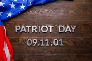 il parole patriota giorno di cui con argento metallo lettere su di legno tavola superficie con spiegazzato Stati Uniti d'America bandiera foto
