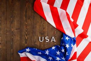 il parola Stati Uniti d'America di cui con argento metallo lettere su di legno tavola superficie sotto spiegazzato bandiera di unito stati di America foto