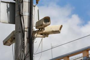 Due vecchio cctv sicurezza sorveglianza macchine fotografiche su strada leggero polo su blu cielo sfondo foto