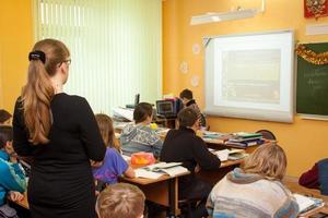 tula, Russia, gennaio 18, 2013, bellissimo giovane insegnante donna in piedi tra seduta studenti nel un' mezzo scuola classe. foto