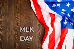 il parola mlk giorno di cui con argento metallo lettere su di legno superficie con spiegazzato Stati Uniti d'America bandiera a giusto lato foto