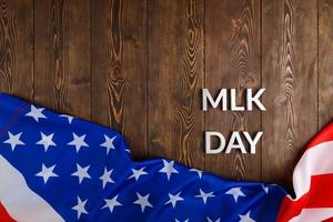 il parola mlk giorno di cui con argento metallo lettere su di legno superficie con spiegazzato Stati Uniti d'America bandiera a inferiore lato foto