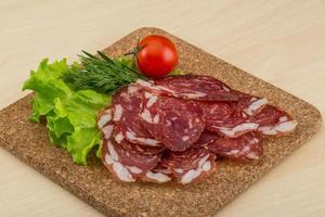 affettato salame su di legno tavola e di legno sfondo foto