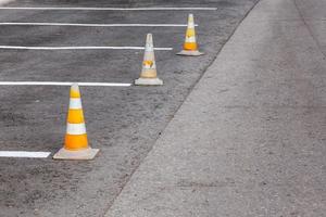 arancia strada coni su un' asfalto guida la zona con bianca Linee foto