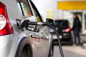 grigio auto rifornimento carburante su gas stazione - avvicinamento con sfocato uomo su sfondo foto