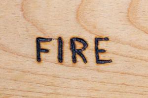 il parola fuoco manoscritto su di legno superficie con elettrico bruciatore a legna foto