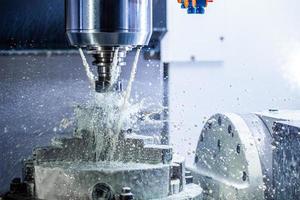 un' processi di industriale bagnato fresatura nel 5 assi cnc macchina con refrigerante flusso sotto pressione e congelato spruzzi foto